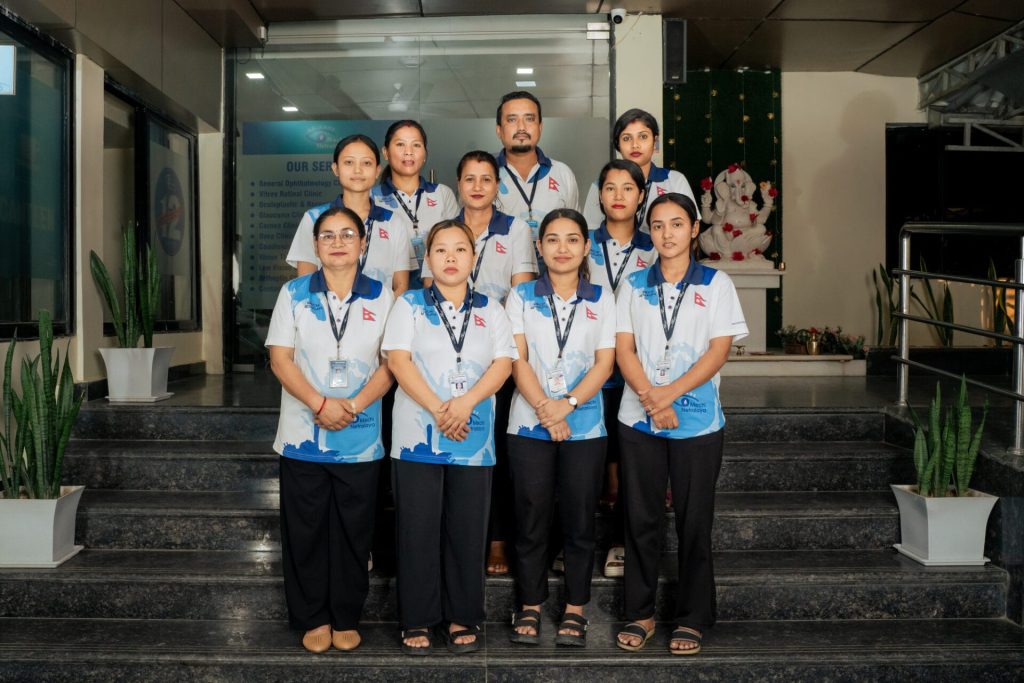 Group of ten staff members posing on steps of Mechi Netralaya