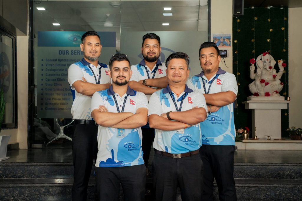 five men in matching uniforms posing in front of eye care clinic
