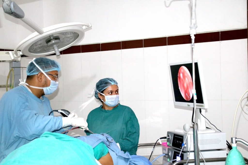 Medical professionals performing surgery with monitor displaying internal view