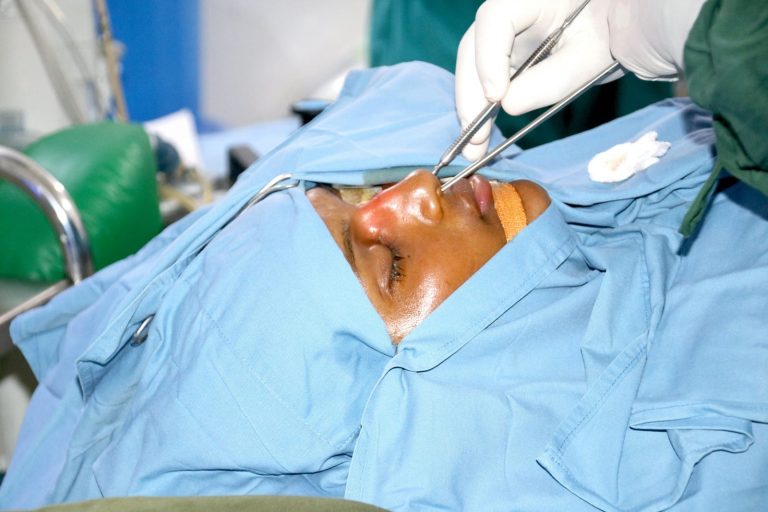 Surgeon performing nose surgery on patient
