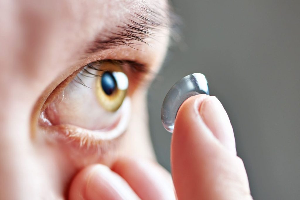 person placing contact lens on finger for eye