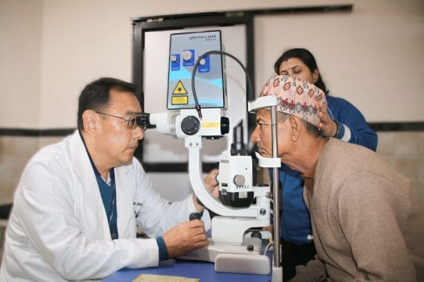 doctor conducting eye examination on patient with assistant