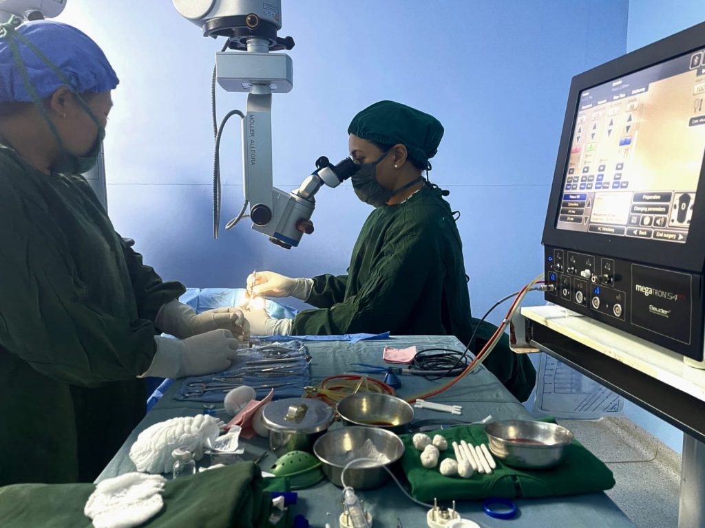 Two surgeons performing eye surgery with microscope and equipment