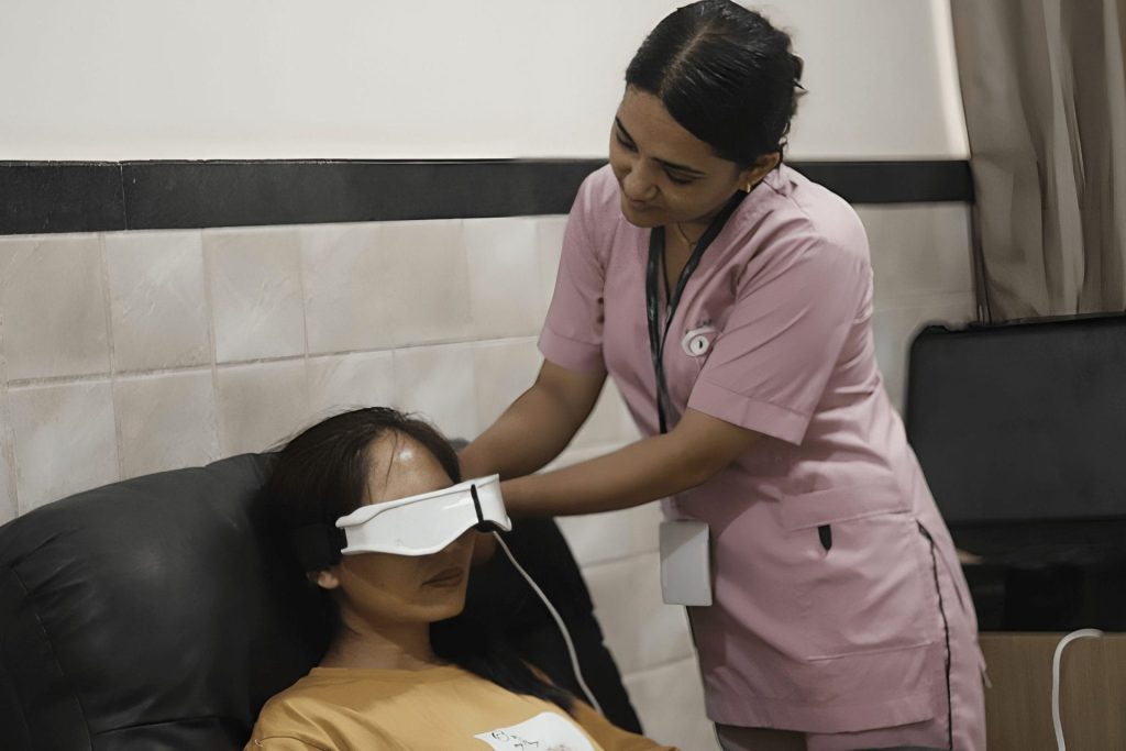 Nurse in pink scrubs performing eye test on patient with white device