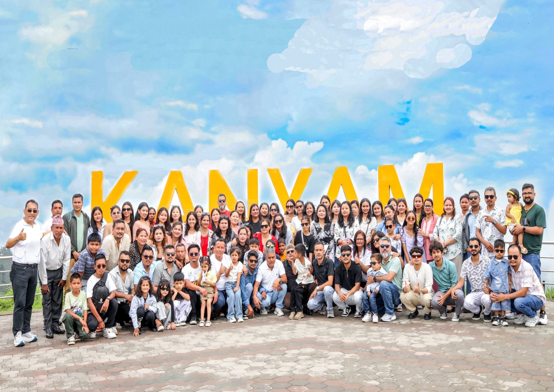 Large group of people posing in front of Kanyam sign