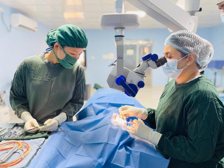 Two surgeons performing eye surgery with medical equipment